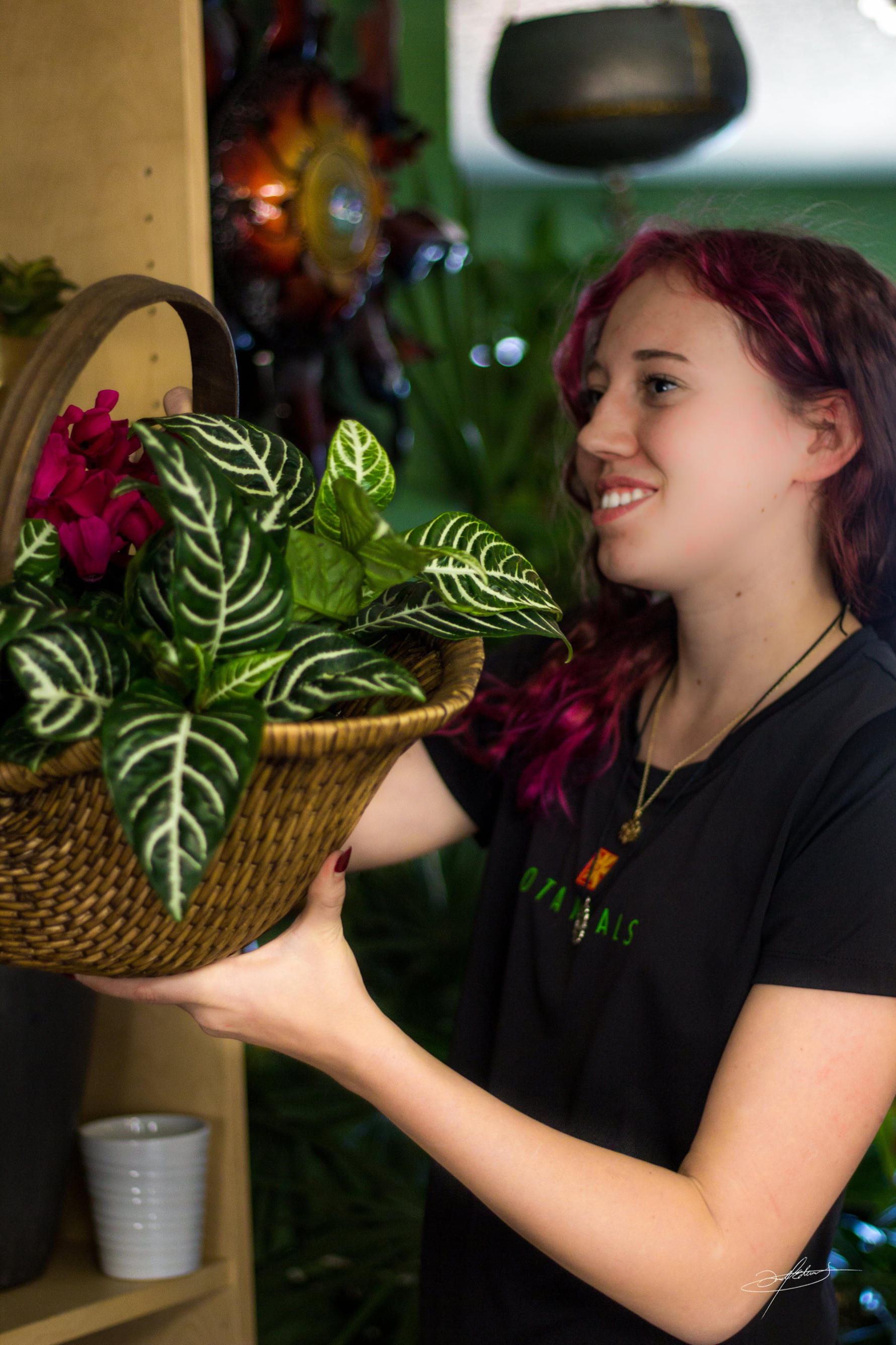 botanicals employee smiling while holding a basket of subtropical plants